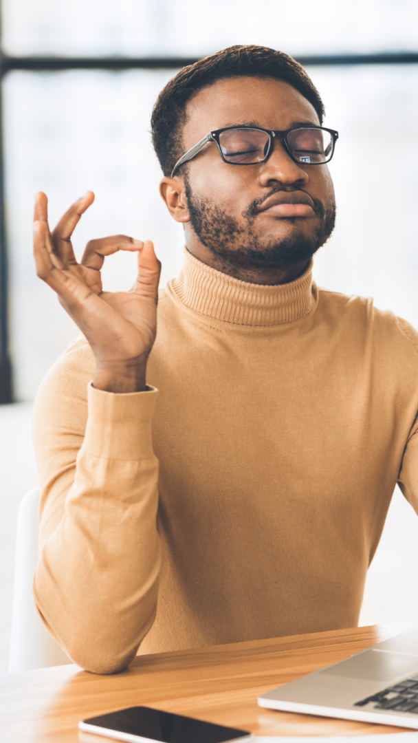 black man meditation | anxiety symptoms Atlanta | anxiety help | anxiety therapy | Atlanta anxiety therapist | 30213 | 30097 | 30126 Image of a Black man in a yellow shirt taking deep breaths while working. Representing someone who could benefit from seeing an Atlanta therapist for their anxiety symptoms. Anxiety therapy can provide you with the help you need.