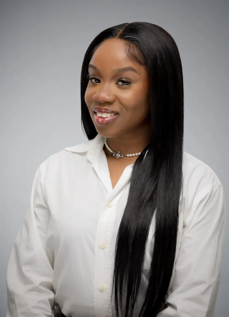 Relationship and Individual Therapy for Young Adults | Atlanta | 30004 | 30022 | 30319 | 30904 | 29821 Black female therapist smiling, wearing white button down shirt in Atlanta offering relationship and individual therapy for young adults.