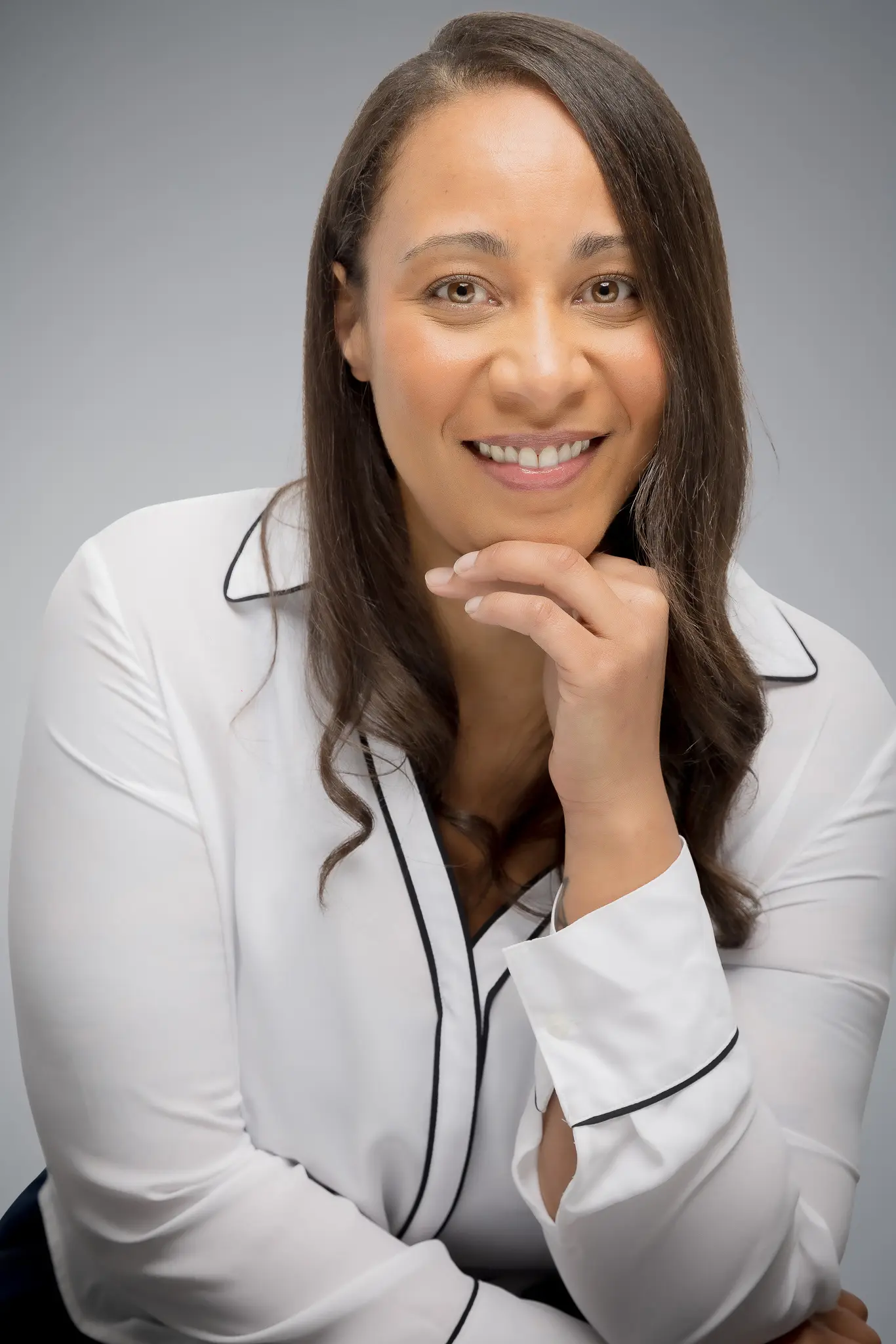 851A3579-1 Black female therapist smiling, wearing white button down shirt in Atlanta offering relationship and individual therapy for young adults.