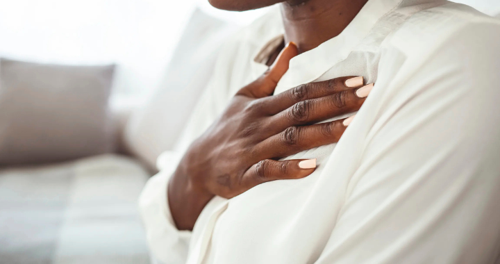 black woman deep breathing | anxiety symptoms Atlanta | anxiety help | anxiety therapy | Atlanta anxiety therapist | 30213 | 30097 | 30126 Image of Black woman practicing deep breathing touching chest sitting on a couch in the living room at home. Representing therapy technique to manage anxiety with an Atlanta therapist.