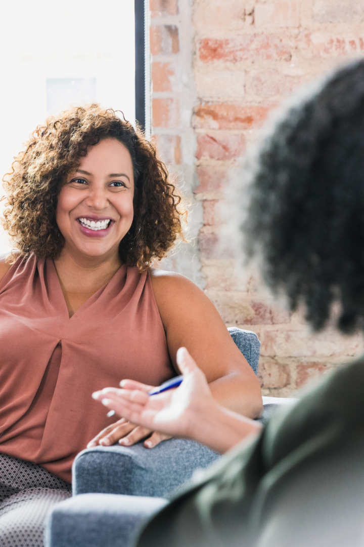 Therapy with a Counselor Intern | Benefits for Black Women | 30126 | 30044 | 30135 | 30004 | 30034 Black woman excitedly talking to a Black female therapist, engaging in therapy with a counselor intern to enhance mental health and personal growth