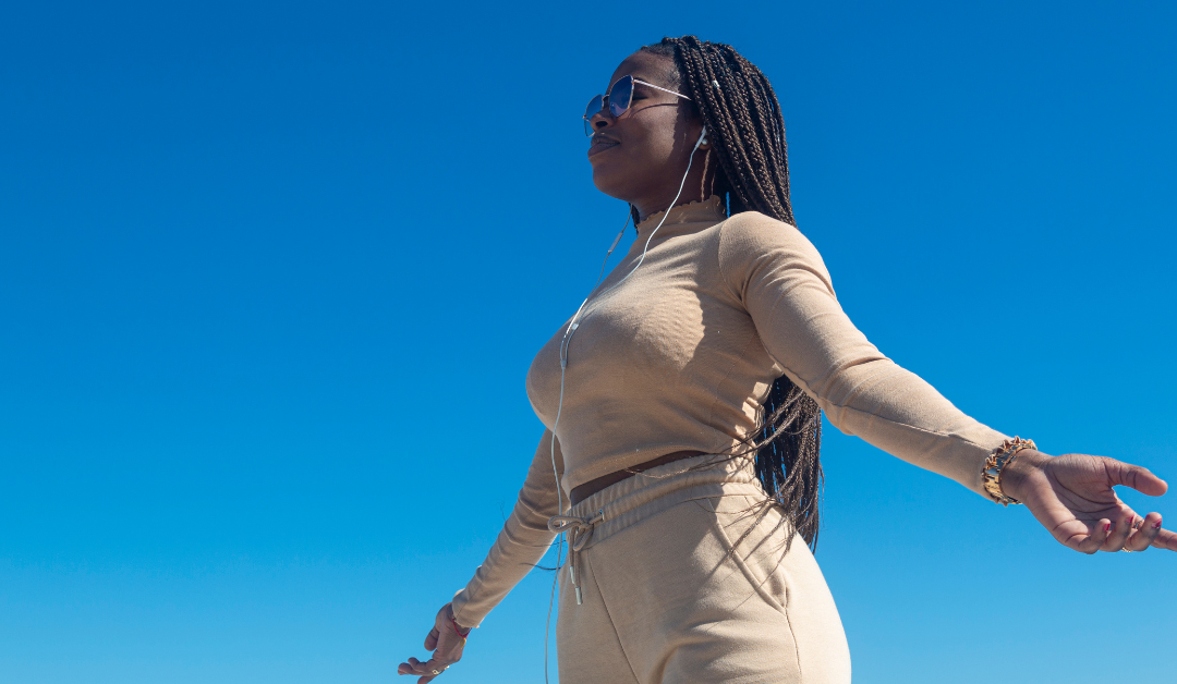 Black woman meditating on a hilltop participating in therapy for managing anxiety and stress.