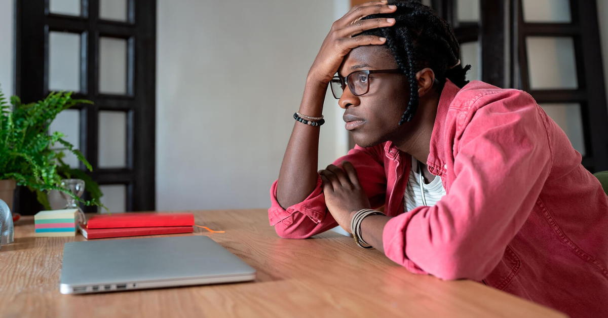 Image of a Black man sitting at his desk looking upset. Showing someone who could benefit from therapy for African American males in Atlanta. Where Black female therapists can provide support through therapy for Black men.