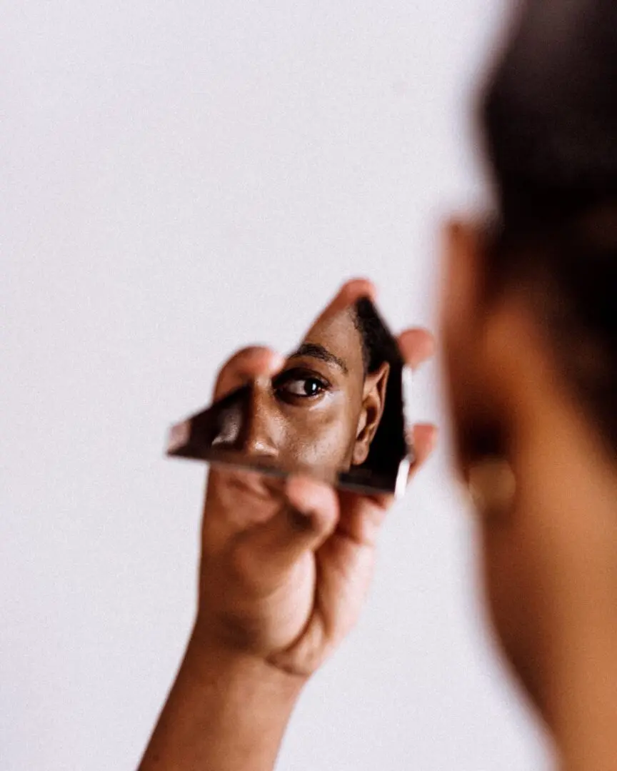 jurien-huggins-jLWlA1HQMbE-unsplash Image of Black woman with anxiety wear a yellow shirt with hand under chin and strained expression. She looks tired.