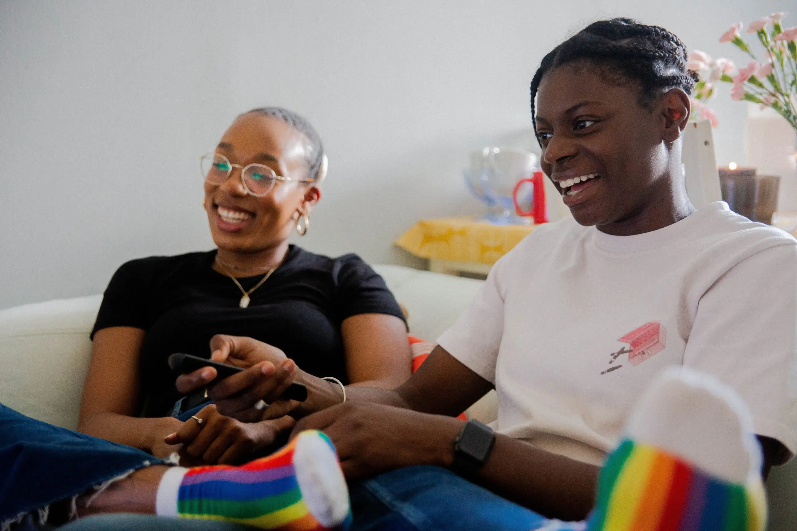 LGBTQ couple | black couples therapy in Atlanta, GA | black couples counseling | Atlanta black couples therapist | black marriage counseling | 30263 | 30044 | 30179 Image of a couple sitting and watching TV together while laughing. Showing that by starting black couples counseling you can end that disconnect. The skills learned in black couples therapy in Atlanta, GA can make the time with your partner more like this.