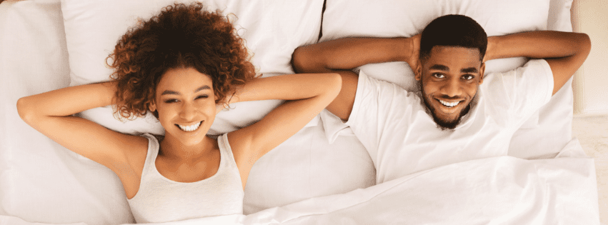 Image of a black couple laying in bed together smiling. This type of connection can be had after starting black couples counseling and black marriage counseling in Atlanta, GA. Start repairing your relationship with support from an Atlanta black couples therapist.