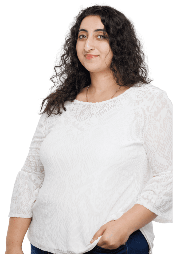 South Asian female therapist in Atlanta, Georgia, radiating warmth in a white top and jeans, offering therapeutic services for anxiety and stress management.