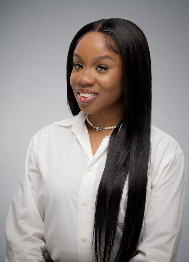 Black female therapist smiling, wearing white button down shirt in Atlanta offering relationship and individual therapy for young adults.