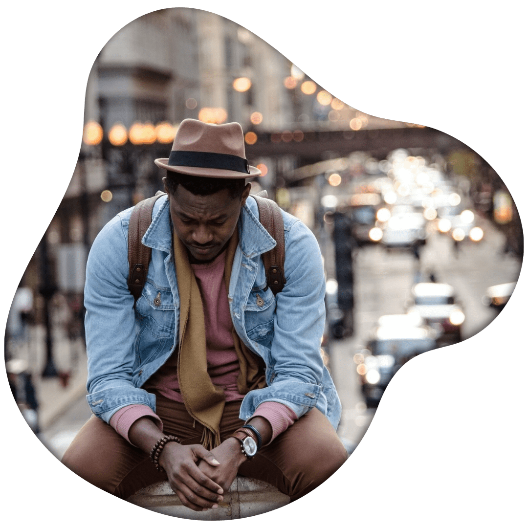 Image of a Black man sitting outside on a raised ledge. Representing someone who is showing signs of grief and could benefit of support of an Atlanta grief counselor. Where with grief counseling he can feel better.