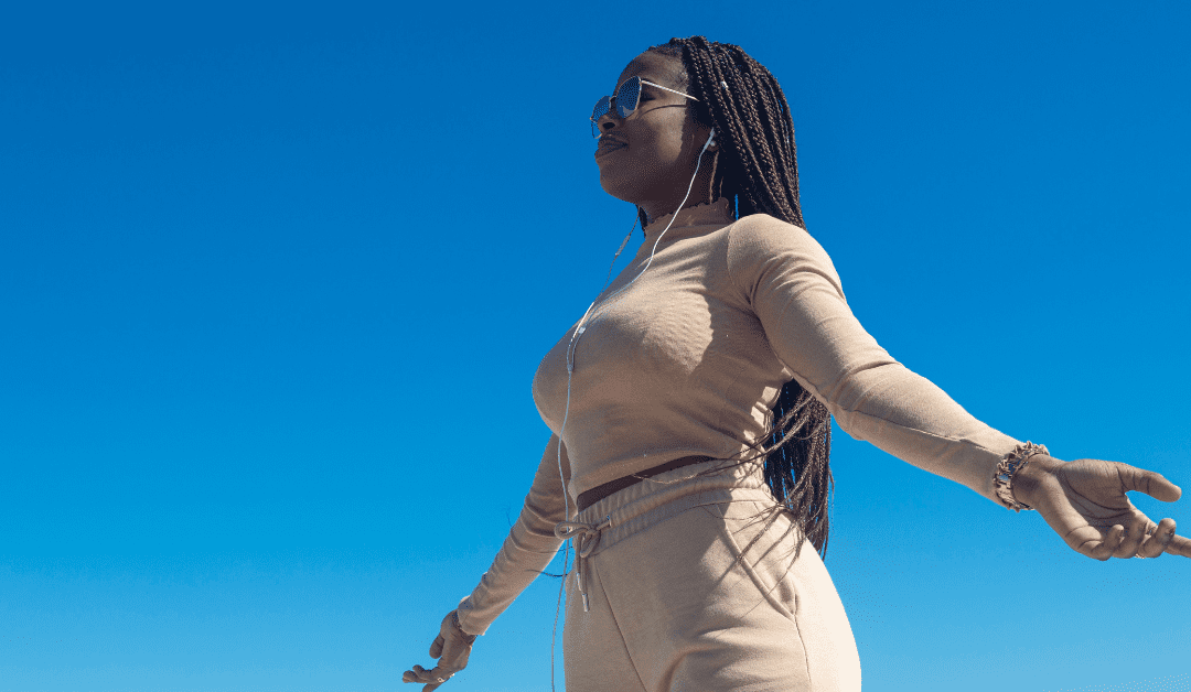 Black woman meditating on a hilltop participating in therapy for managing anxiety and stress.