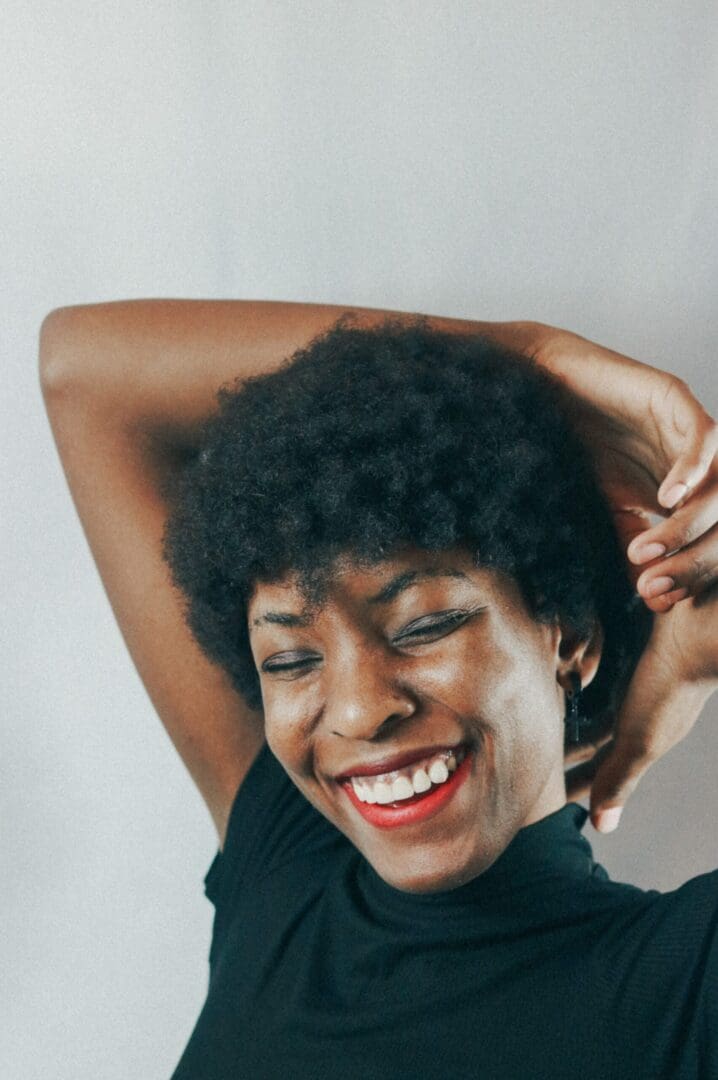 Black woman smiling, reflecting the positive journey of overcoming low self-esteem and building confidence.