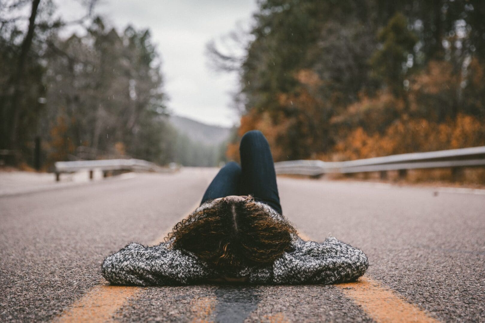 Woman lying on a mountain, arms behind her head, gazing at the sky in a peaceful and reflective moment of self-care